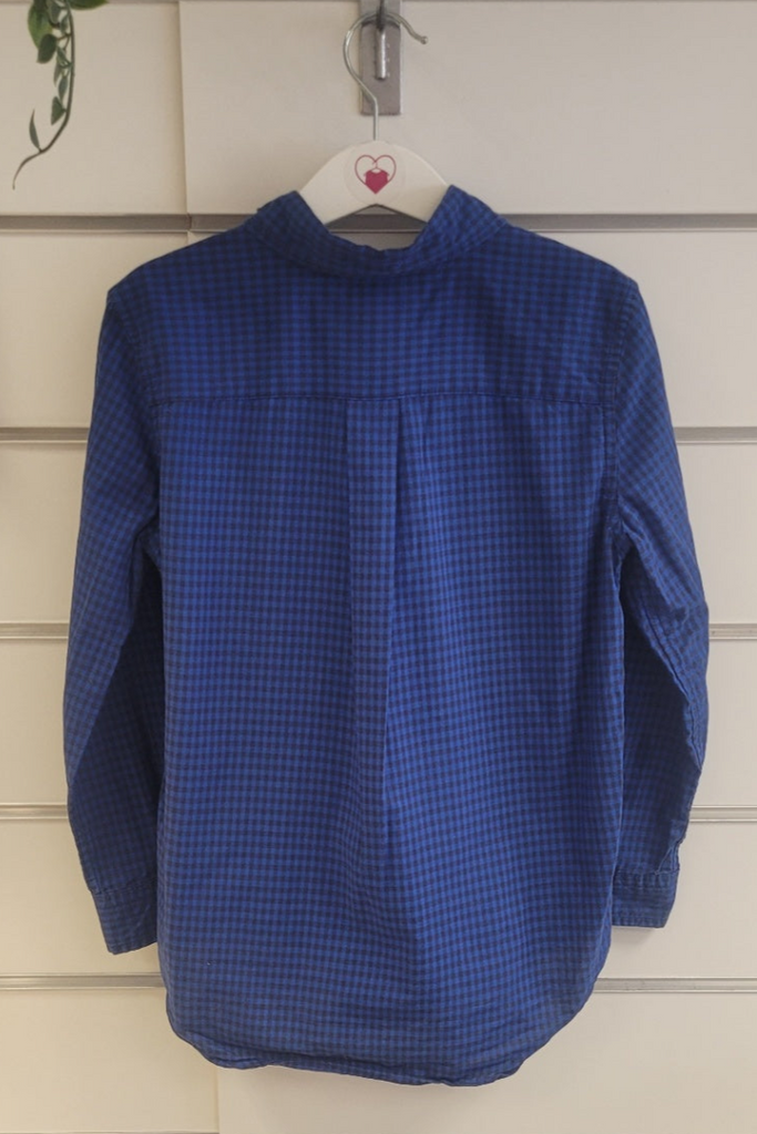 Blue textured shirt hanging on a white wall