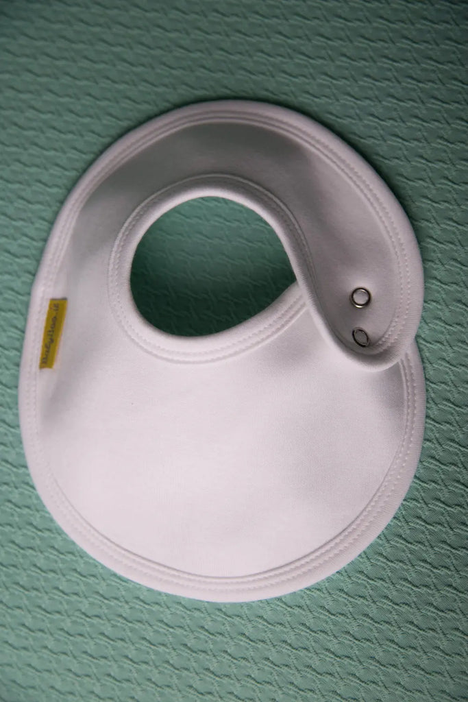 White baby bib on a green textured surface