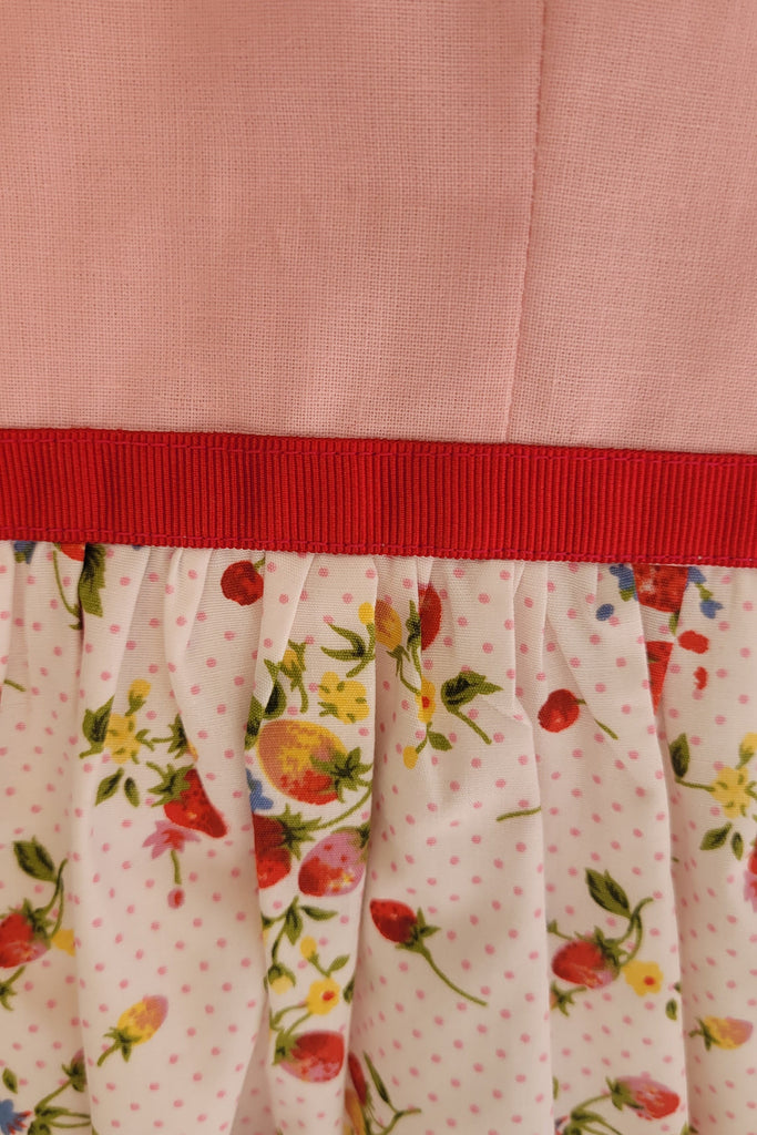 Close-up of a quilt with floral pattern and red border on pink fabric background