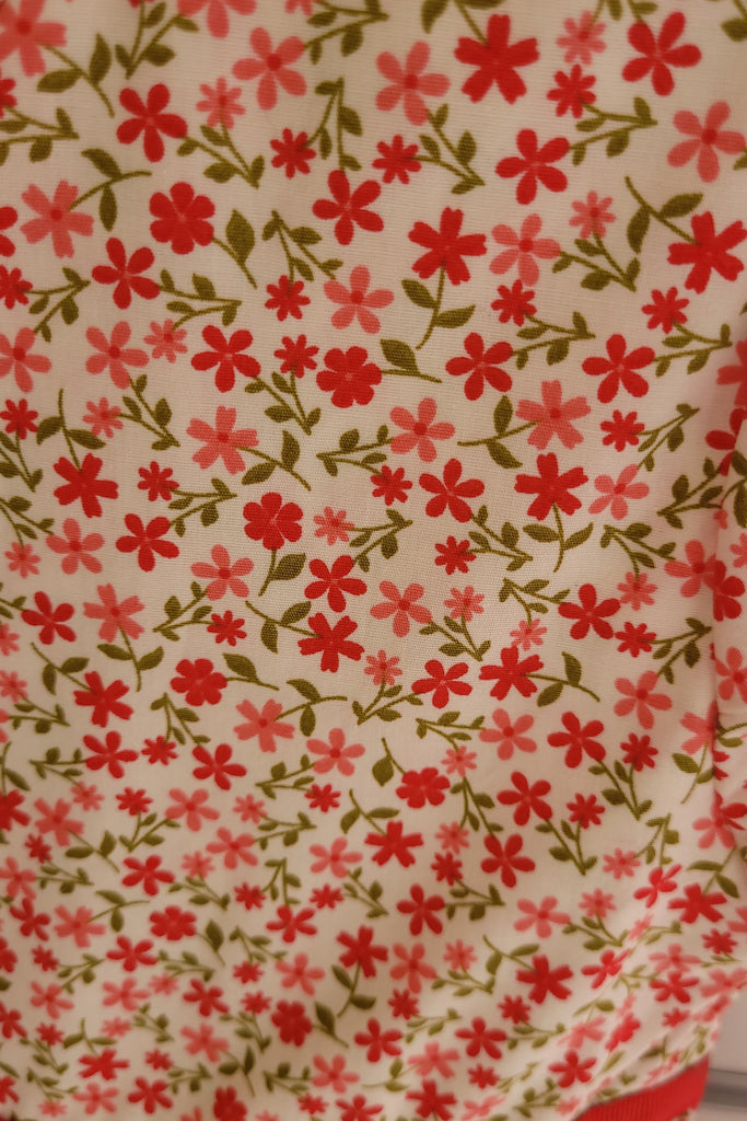 Floral patterned fabric with red and pink flowers on a beige background